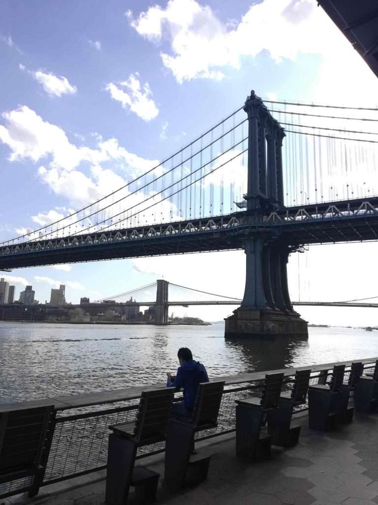 man texting by Manhattan Bridge NYC
