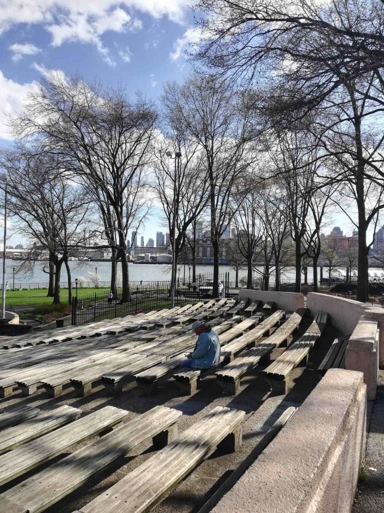 Man texting at East River stage bench nyc