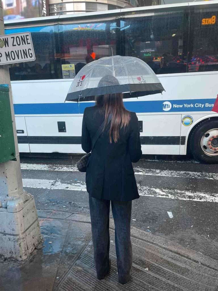 Lady waiting to cross street holding umbrella